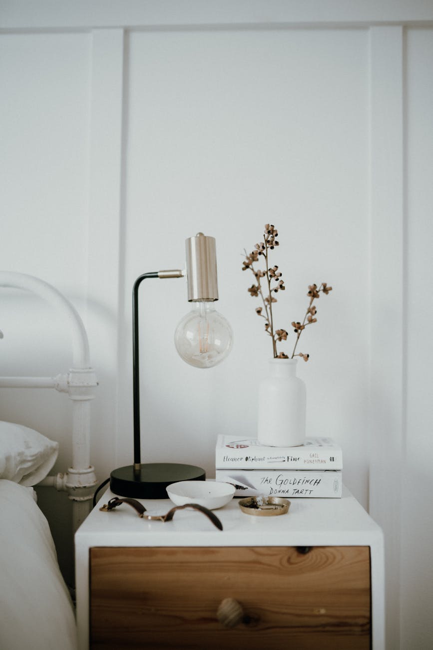 a white ceramic vase on the bedside table